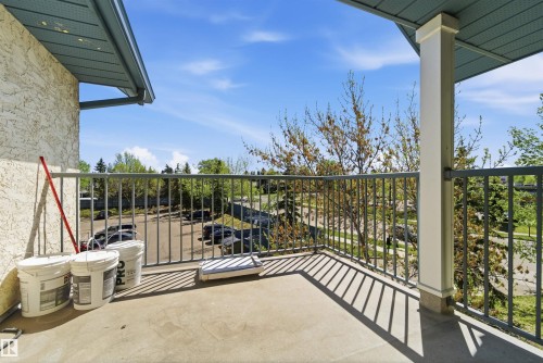 Concrete balcony featuring a durable metal railing, a stucco exterior facade, and an overhead soffit with integrated lighting - 302 2508 50 Street Nw, Edmonton, AB - Outdoor With Exterior