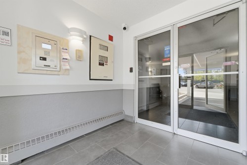 Entrance featuring full-light glass doors with white frames, a gray tiled floor, and a wall-mounted intercom system - 302 2508 50 Street Nw, Edmonton, AB -  Photo Showing Other Room