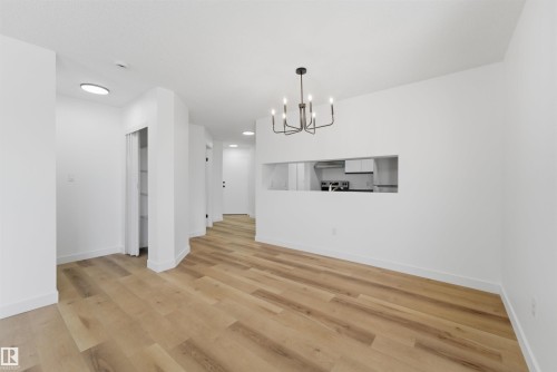 Open-concept living area featuring wood-finish flooring, a modern black chandelier, and recessed lighting - 302 2508 50 Street Nw, Edmonton, AB - Indoor Photo Showing Other Room