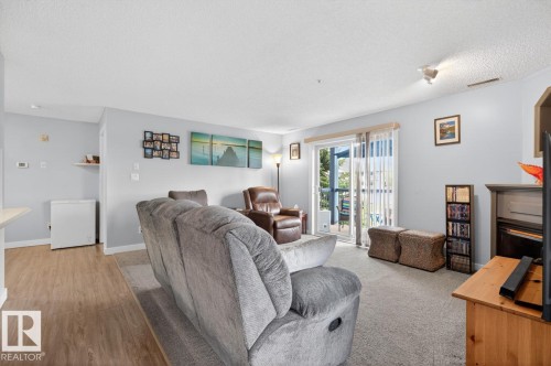 Living area featuring wood-finish flooring, a carpeted section, and light-colored walls - 220 16303 95 Street, Edmonton, AB - Indoor Photo Showing Living Room