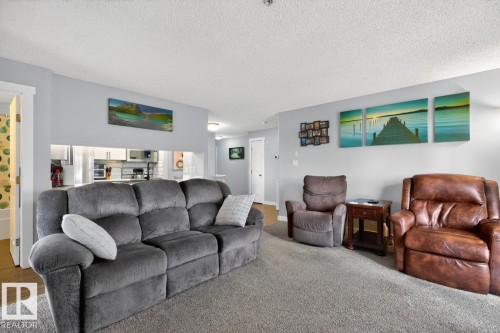 Carpeted living area featuring light gray walls and a textured ceiling - 220 16303 95 Street, Edmonton, AB - Indoor Photo Showing Living Room