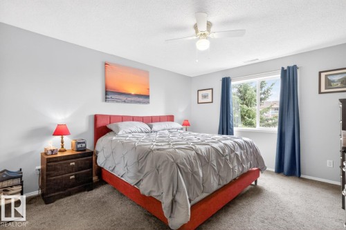 Carpeted bedroom with light gray walls, a ceiling fan with light fixture, and a large window - 220 16303 95 Street, Edmonton, AB - Indoor Photo Showing Bedroom