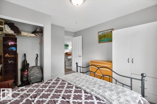 Light gray painted walls define this interior space, featuring a built-in closet with wire shelving - 220 16303 95 Street, Edmonton, AB - Indoor Photo Showing Bedroom
