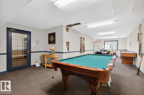 Recreational space featuring a full-size billiards table, carpet tile flooring, and a glass-paneled door - 220 16303 95 Street, Edmonton, AB - Indoor Photo Showing Other Room