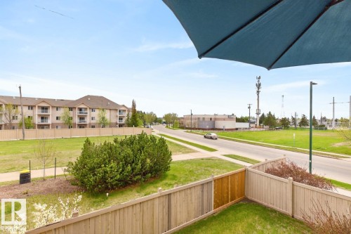 Fenced backyard featuring a manicured lawn, a wooden fence, and mature shrubs - 220 16303 95 Street, Edmonton, AB - Outdoor With Balcony
