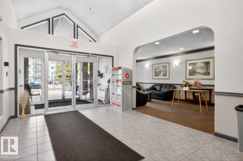 Spacious building entrance featuring a vaulted ceiling and an arched doorway leading to a common area - 220 16303 95 Street, Edmonton, AB - Indoor
