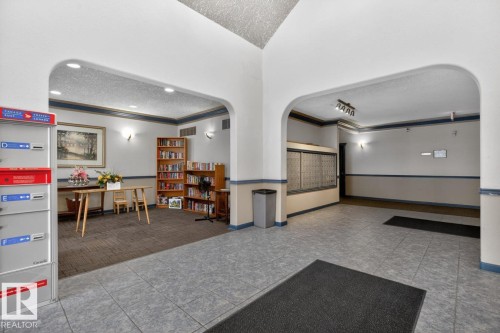 Building common area featuring arched doorways, tiled flooring, recessed lighting, and wall sconces - 220 16303 95 Street, Edmonton, AB - Indoor Photo Showing Other Room