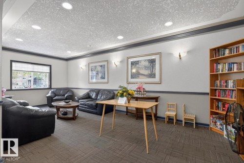 Welcoming common area featuring recessed lighting, crown molding, wall sconces, a built-in bookshelf, and patterned carpeting - 220 16303 95 Street, Edmonton, AB - Indoor