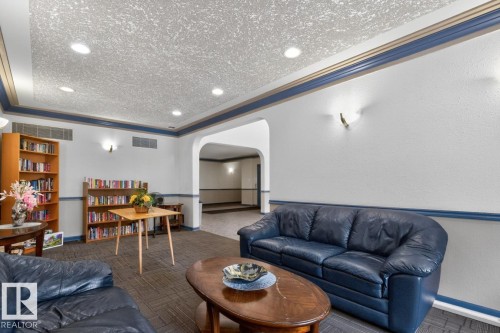 Lounge area featuring recessed lighting, wall sconces, textured ceiling, and an arched entry - 220 16303 95 Street, Edmonton, AB - Indoor Photo Showing Living Room