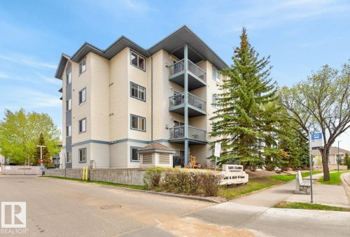 Multi-story residential building featuring light-colored siding with dark trim accents, multiple private balconies with metal railings, and a prominent pitched roofline - 220 16303 95 Street, Edmonton, AB - Outdoor With Balcony