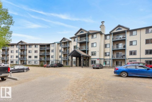 Multi-story building featuring a beige facade with darker trim, multiple balconies, and a covered main entrance - 220 16303 95 Street, Edmonton, AB - Outdoor With Balcony With Facade