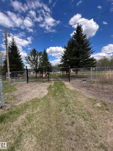 Gated entry with a black metal double gate, wire fencing, and mature evergreen trees - #41 59419 Rge Rd 240, Rural Westlock County, AB - Outdoor With View