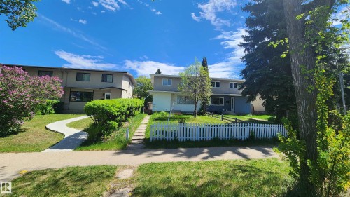 Two-story residence featuring a white picket fence and a mature tree - 4709 106 Street, Edmonton, AB - Outdoor