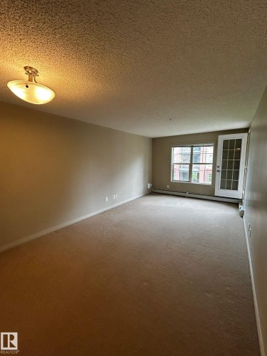 Spacious room featuring neutral carpeting and wall tones - 205 11445 Ellerslie Road, Edmonton, AB 