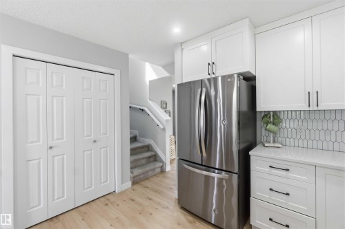 Modern kitchen featuring white shaker-style cabinetry, stainless steel French-door refrigerator, and a white picket tile backsplash - 5129 Lark Crescent, Edmonton, AB - Indoor Photo Showing Kitchen