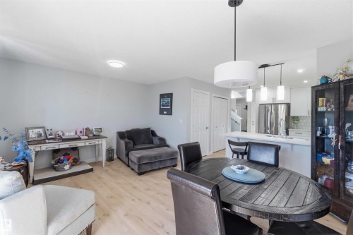 Open-concept living space featuring wood-finish flooring, a contemporary dining area with a drum pendant light, and a kitchen with a breakfast bar - 5129 Lark Crescent, Edmonton, AB - Indoor