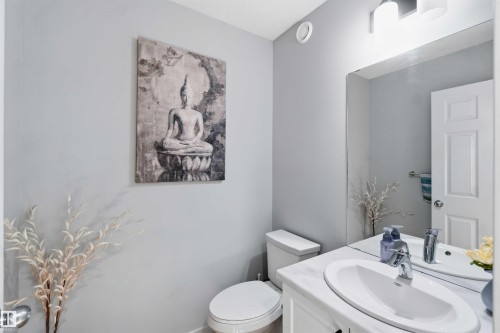 Bathroom featuring light gray walls, a white vanity with an undermount sink, a chrome faucet, and a large wall-mounted mirror - 5129 Lark Crescent, Edmonton, AB - Indoor Photo Showing Bathroom