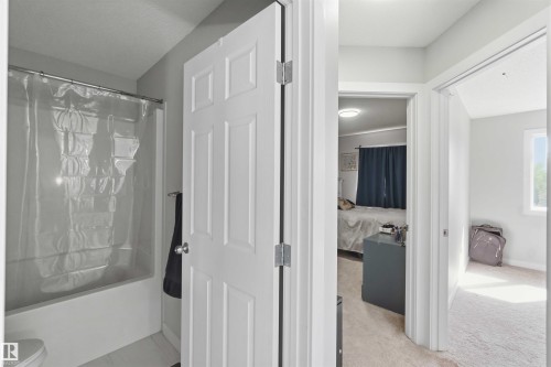 Full bathroom featuring a white tub-shower combination with a clear shower curtain and a white panel door - 5129 Lark Crescent, Edmonton, AB - Indoor Photo Showing Bathroom