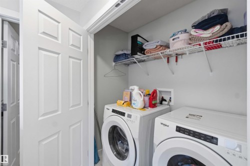 Dedicated laundry area featuring a white six-panel door, light gray wall paint, and integrated wire shelving for storage - 5129 Lark Crescent, Edmonton, AB - Indoor Photo Showing Laundry Room