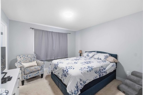 Carpeted room with a ceiling-mounted light fixture and a window featuring dark-colored drapes - 5129 Lark Crescent, Edmonton, AB - Indoor Photo Showing Bedroom
