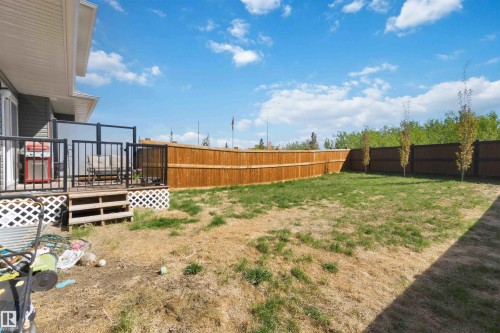Expansive backyard featuring a new wooden fence, a multi-level deck with glass and metal railings, and a side access door to the property - 5129 Lark Crescent, Edmonton, AB - Outdoor