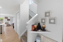 Light wood-finish flooring extending through the main level, complemented by a staircase with carpeted treads and white risers - 5129 Lark Crescent, Edmonton, AB  - Indoor 