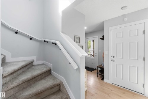 Carpeted staircase with white handrail and black supports, complemented by light wood-finish flooring - 5129 Lark Crescent, Edmonton, AB - Indoor Photo Showing Other Room