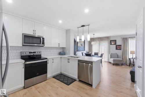 Contemporary kitchen featuring white cabinetry, stainless steel appliances, light countertops, and a subway tile backsplash - 5129 Lark Crescent, Edmonton, AB - Indoor Photo Showing Kitchen With Double Sink With Upgraded Kitchen