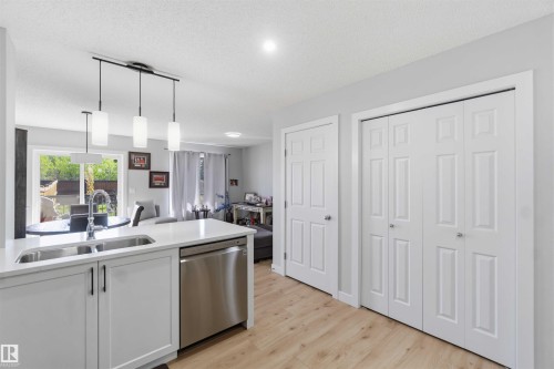 Kitchen island featuring a double basin stainless steel sink, pull-down faucet, and white quartz countertop - 5129 Lark Crescent, Edmonton, AB - Indoor Photo Showing Kitchen With Double Sink