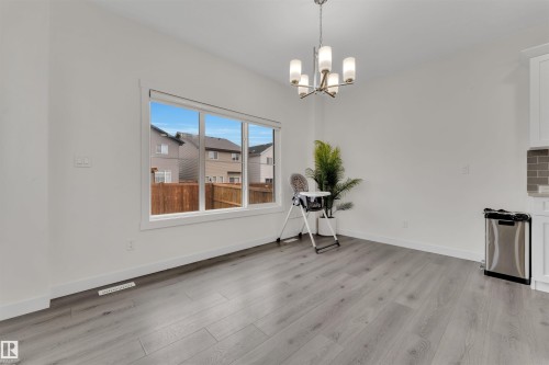 Open-concept dining area featuring light wood-finish flooring, a contemporary chandelier, and a large window - 22534 98A Avenue, Edmonton, AB - Indoor Photo Showing Other Room