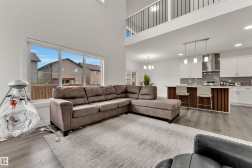 Open-concept living space featuring high ceilings, wood-finish flooring, and a kitchen island with seating - 22534 98A Avenue, Edmonton, AB - Indoor Photo Showing Living Room