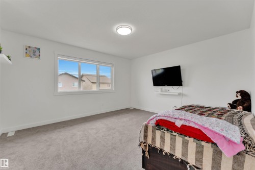 Bright interior with a large window, plush gray carpet, white baseboards, and a contemporary ceiling light fixture - 22534 98A Avenue, Edmonton, AB - Indoor Photo Showing Bedroom