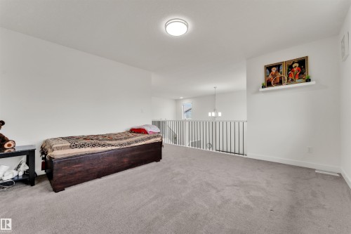 Open loft area featuring neutral carpeting, white walls, and a contemporary ceiling light fixture - 22534 98A Avenue, Edmonton, AB - Indoor