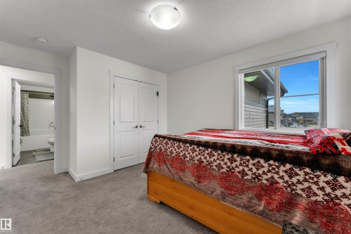 Carpeted room featuring a large window, a double-door closet, and an entry to a bathroom with a shower-tub combination - 22534 98A Avenue, Edmonton, AB - Indoor Photo Showing Bedroom