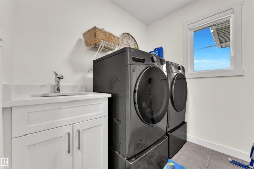 Laundry area featuring a white vanity with an undermount sink, a chrome faucet, and a white countertop - 22534 98A Avenue, Edmonton, AB - Indoor Photo Showing Laundry Room