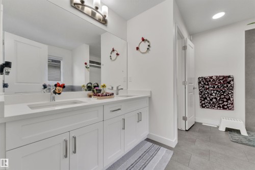 Double vanity with white cabinetry, integrated sinks, chrome fixtures, and a large wall-mounted mirror - 22534 98A Avenue, Edmonton, AB - Indoor Photo Showing Bathroom
