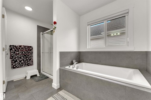 Soaking tub with chrome fixtures, surrounded by gray tile and a privacy window - 22534 98A Avenue, Edmonton, AB - Indoor Photo Showing Bathroom