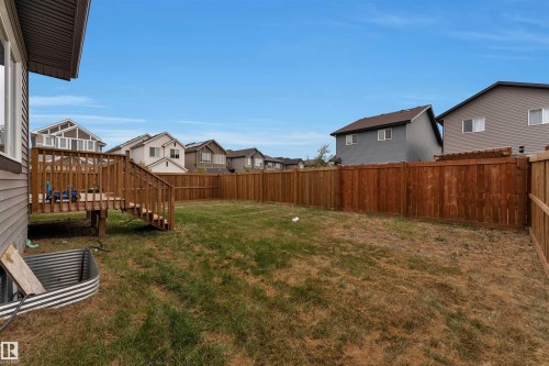 Expansive backyard featuring a wood deck with stairs, a full privacy fence, and a grass lawn - 22534 98A Avenue, Edmonton, AB - Outdoor