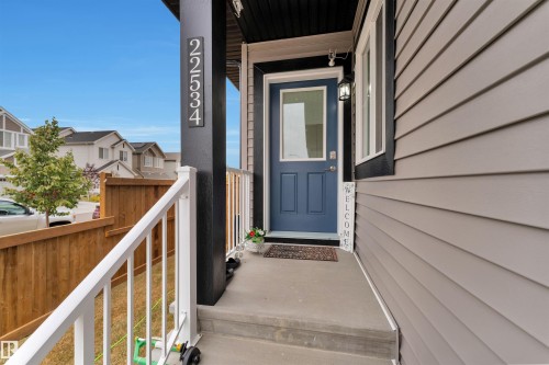 Front entry featuring a blue door with upper glass panel, a white railing, and a black support pillar with house numbers - 22534 98A Avenue, Edmonton, AB - Outdoor With Exterior