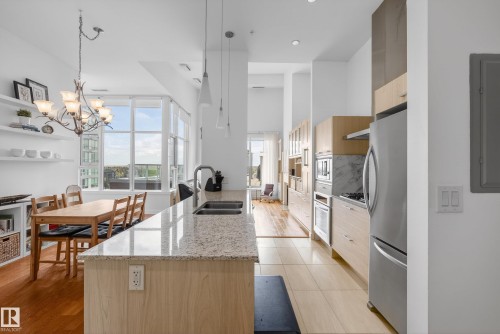Kitchen featuring a granite-finish island with double basin sink, stainless steel appliances, wood-finish cabinetry, and recessed lighting - 808 2612 109 Street, Edmonton, AB - Indoor
