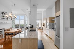 Kitchen featuring a granite-finish island with double basin sink, stainless steel appliances, wood-finish cabinetry, and recessed lighting - 