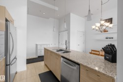 Kitchen island featuring a double-basin sink, light-toned granite countertop, and integrated stainless steel dishwasher - 