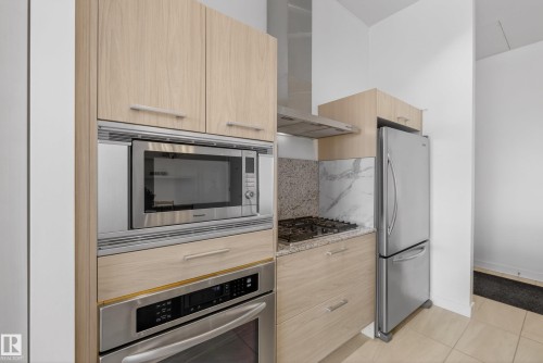 Modern kitchen featuring light wood-finish cabinetry, stainless steel appliances, a built-in microwave, and a gas range - 808 2612 109 Street, Edmonton, AB - Indoor Photo Showing Kitchen