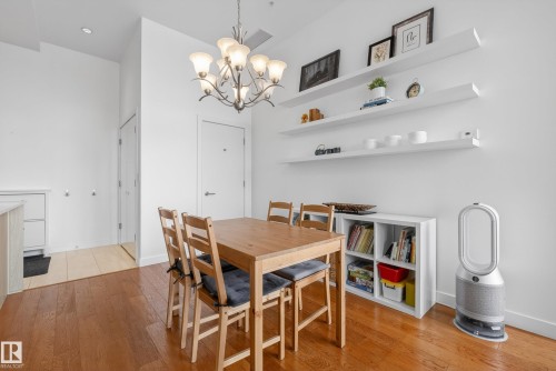 Dining area featuring wood-finish flooring, a multi-light chandelier, and three long wall-mounted shelves - 808 2612 109 Street, Edmonton, AB - Indoor Photo Showing Dining Room