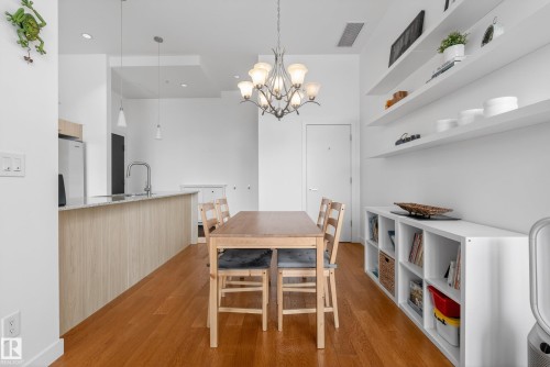 Open-concept living space featuring wood-finish flooring, a kitchen island with stone-look countertops, and a ceiling-mounted chandelier - 808 2612 109 Street, Edmonton, AB - Indoor Photo Showing Other Room