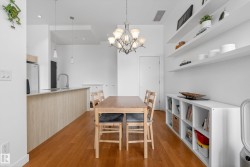 Open-concept living space featuring wood-finish flooring, a kitchen island with stone-look countertops, and a ceiling-mounted chandelier - 