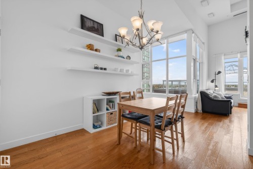 Open-concept living space with wood-finish flooring, a contemporary chandelier, and expansive windows - 808 2612 109 Street, Edmonton, AB - Indoor Photo Showing Dining Room