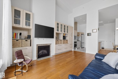 High ceilings complement the wood-finish flooring throughout this living area - 808 2612 109 Street, Edmonton, AB - Indoor Photo Showing Living Room With Fireplace