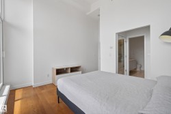 Hardwood flooring and high ceilings characterize this bedroom space - 