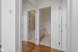 Hallway with wood-finish flooring, white walls, and bright overhead lighting - 